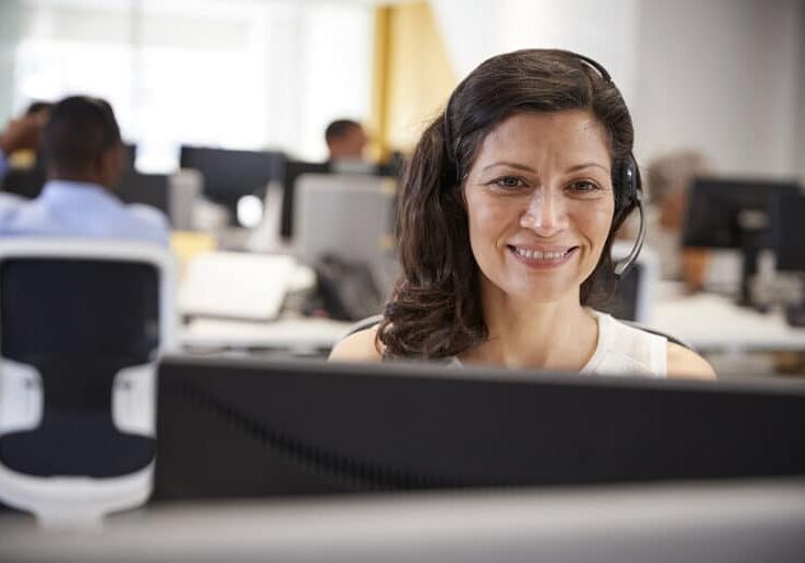 Middle aged woman working at computer with headset in office