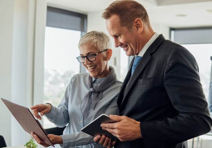 Happy senior business people smiling when looking at digital tablet