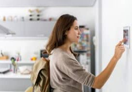 Latin American woman leaving her house and locking the door using a home automation system - security concepts. **DESIGN ON SCREEN BELONGS TO US**