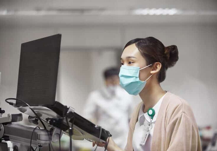 Female nurse using laptop while making medical record. Healthcare worker is concentrating while working in laboratory. She is looking wearing uniform.