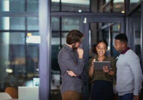 Shot of a group of young businesspeople using a digital tablet together during a late night at work