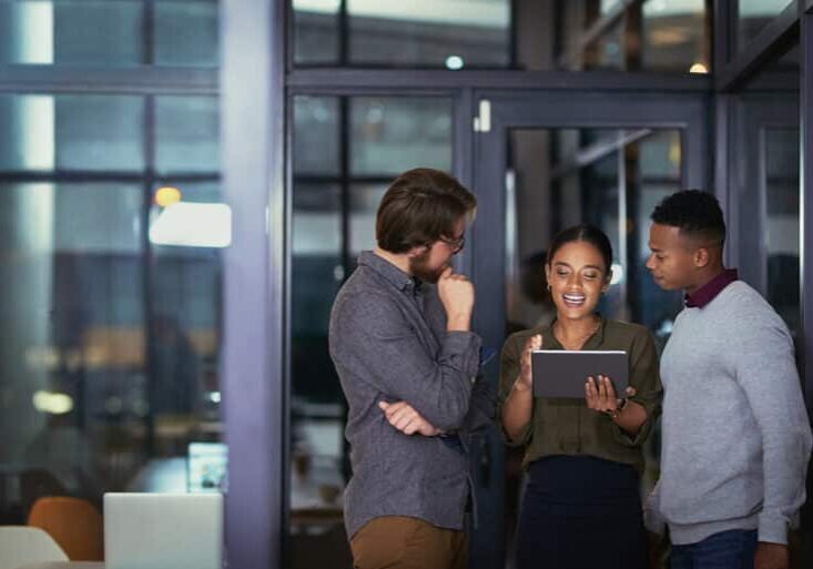 Shot of a group of young businesspeople using a digital tablet together during a late night at work