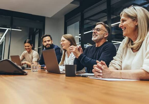 Cheerful business professionals laughing during a briefing. Group of happy businesspeople enjoying working together in a modern workplace. Team of diverse colleagues having a meeting in a boardroom.