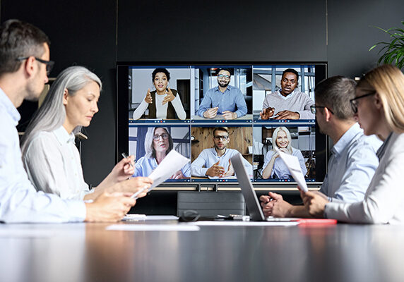 Global corporation online videoconference in meeting room with diverse people sitting in modern office and multicultural multiethnic colleagues on big screen monitor. Business technologies concept.